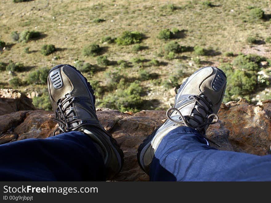 Rock climber resting on the edge, with his feet hanging over the cliff. Rock climber resting on the edge, with his feet hanging over the cliff.