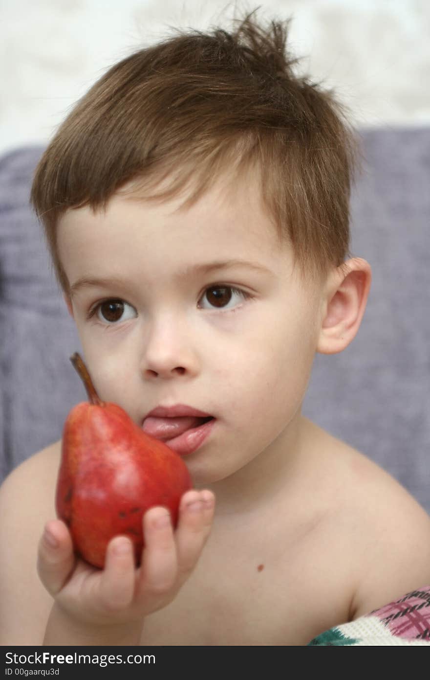 The boy holds a red pear