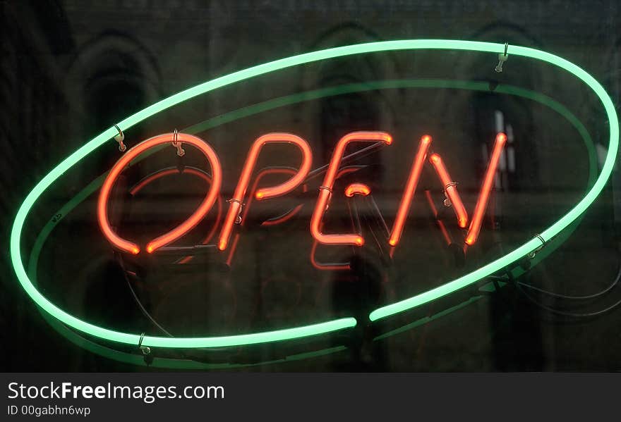 Open, shining neon sign mirroring the windows of the opposite church