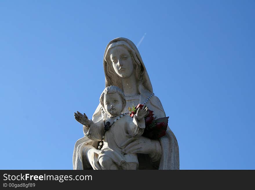 A statue of madonna and the child on a blue sky. A statue of madonna and the child on a blue sky