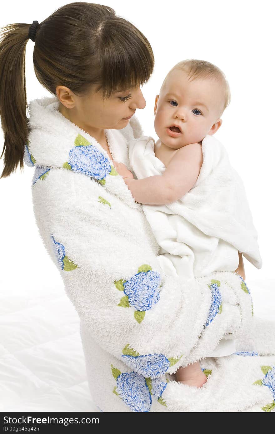 Young mother in bathrobe holding baby boy in towel. White background. Side view. Young mother in bathrobe holding baby boy in towel. White background. Side view