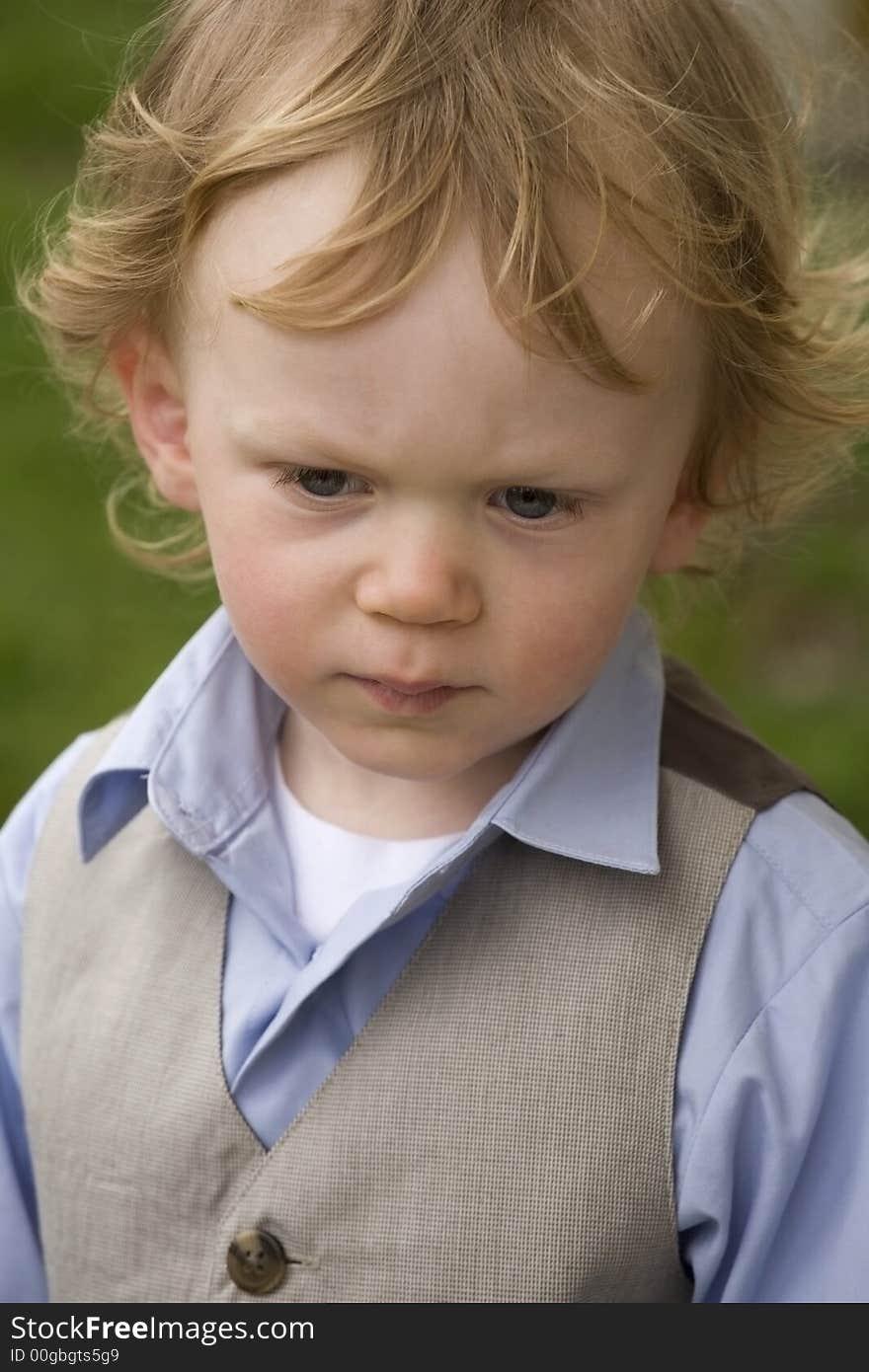 A dressed up boy outside deep in thought. A dressed up boy outside deep in thought