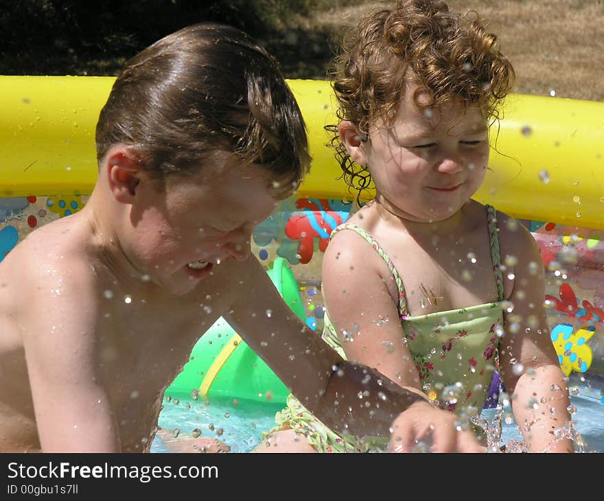 Boy in girl splashing in colorful pool. Boy in girl splashing in colorful pool.