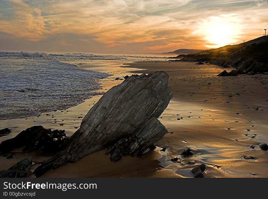 Sunset at the coast with a rock in the foreground and sea in the background. Sunset at the coast with a rock in the foreground and sea in the background