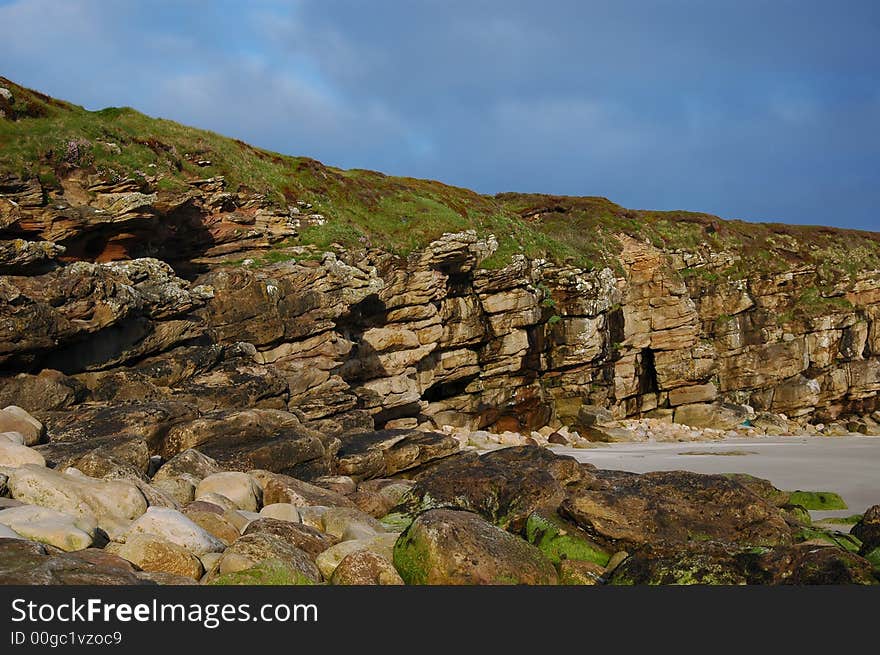 The landfall rocks and low cliffs showing erosion and geological formation of a rocky bay.