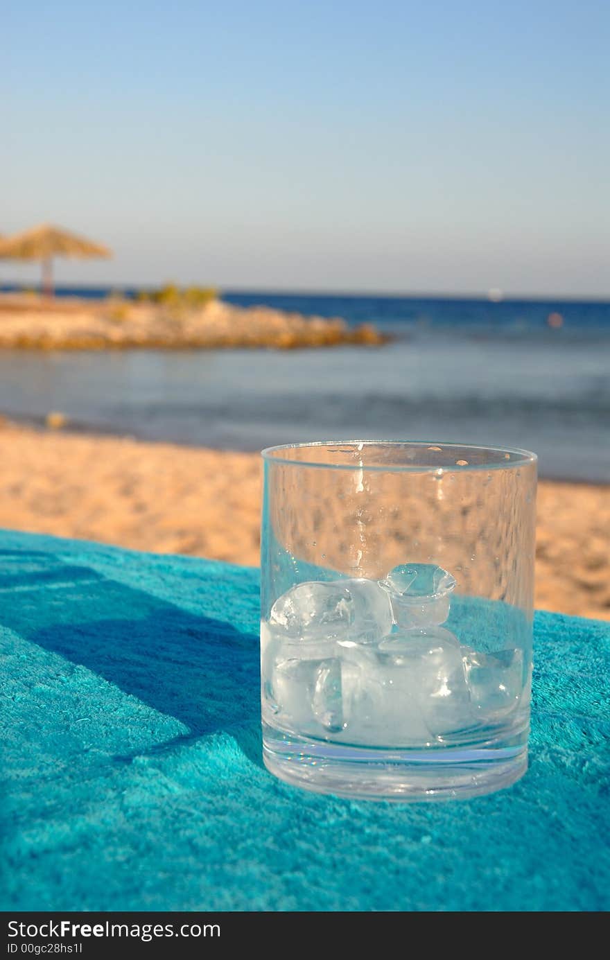 Glass with ice on a background of the sea