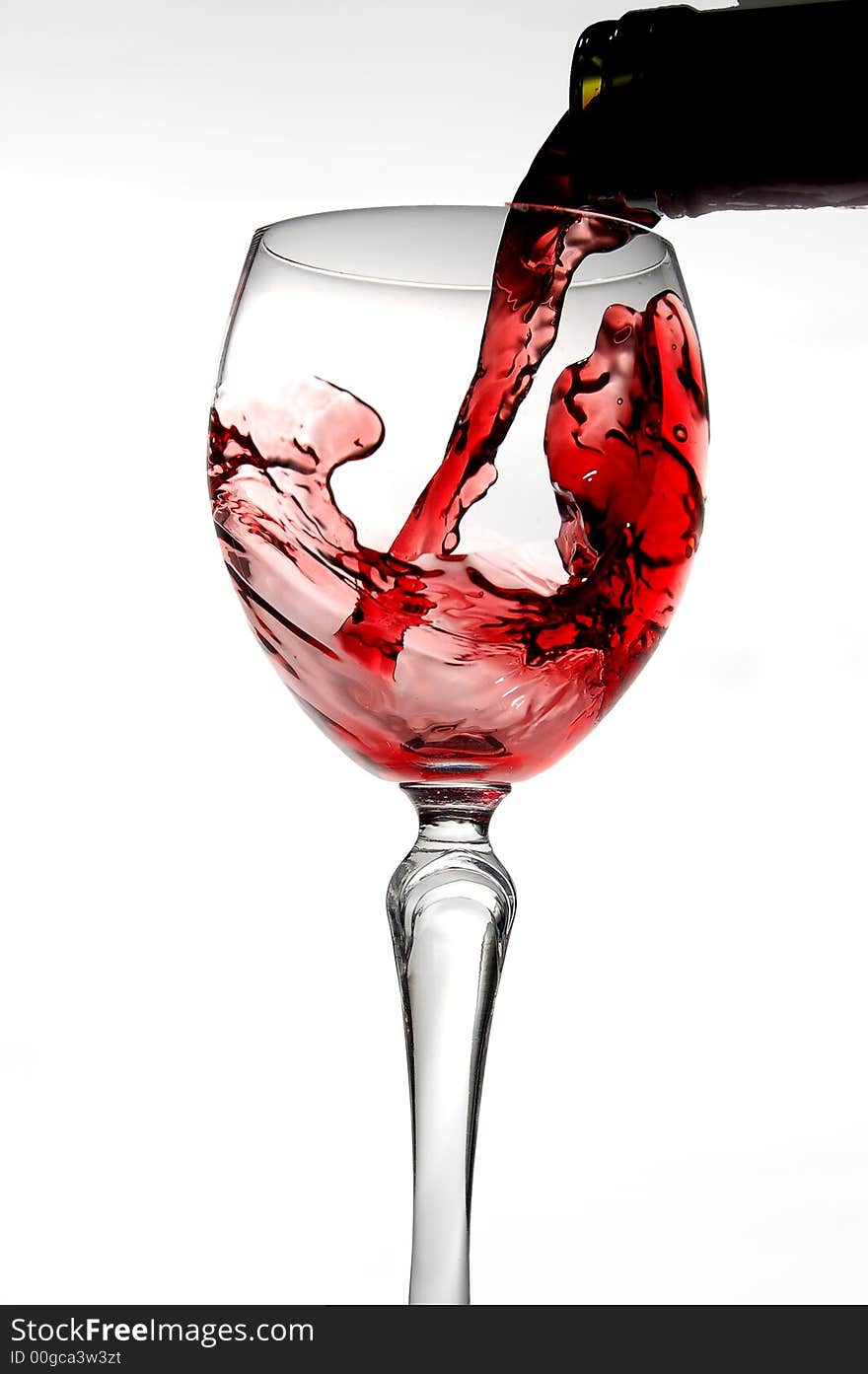 Red wine pouring into glass isolated on white background