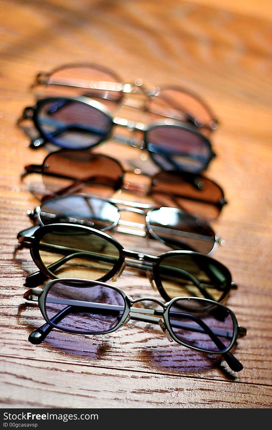 Row of Different Colored Sunglasses on Wooden Floor. Row of Different Colored Sunglasses on Wooden Floor