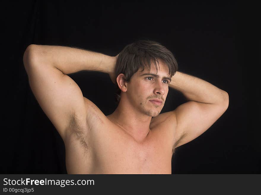 Portrait of young man standing with no shirt on over black background