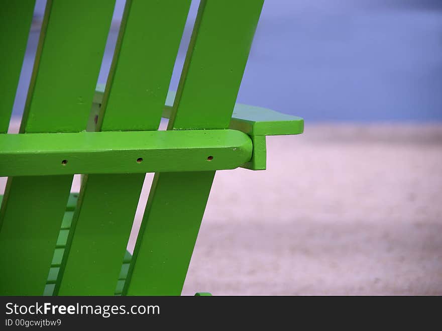 A bright green beach chair breaks the monotone stretch of a tropical beach. A bright green beach chair breaks the monotone stretch of a tropical beach