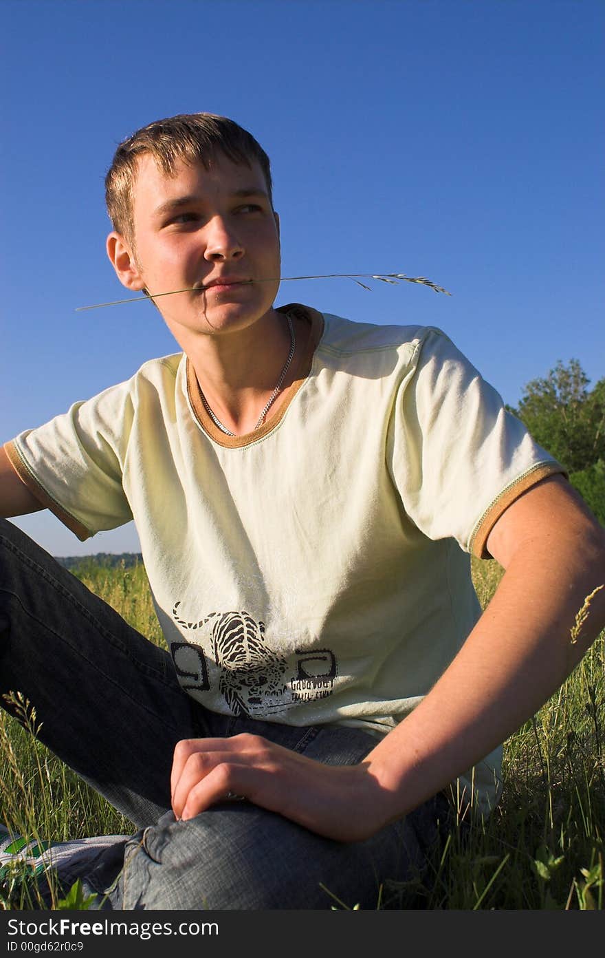 The young man with a blade in a teeth on deep blue sky