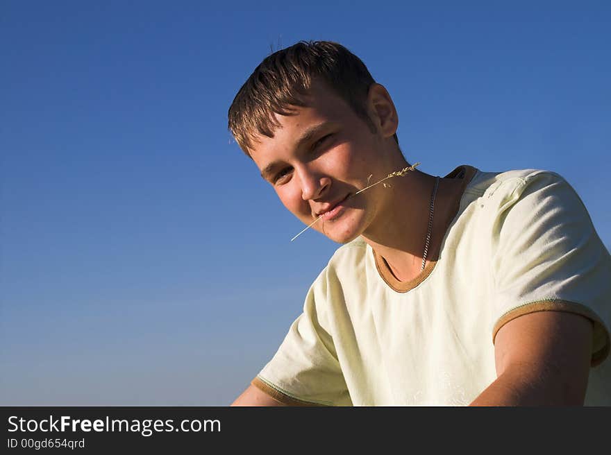 The young man with a blade in a teeth on deep blue sky