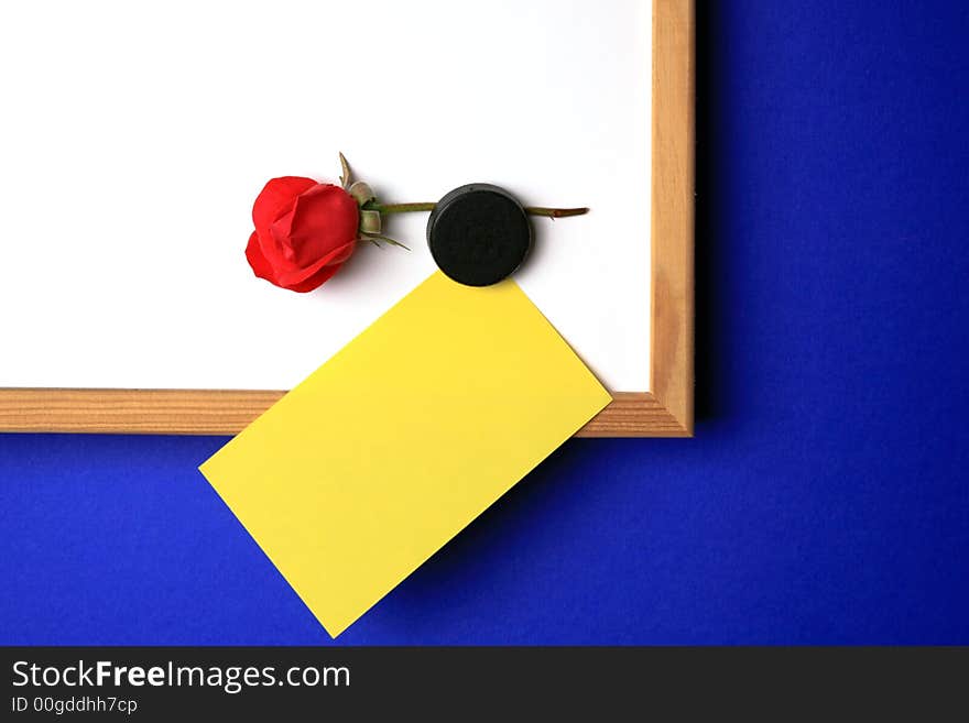 Whiteboard with empty yellow post-it note and magnet in the form of a hart. Whiteboard with empty yellow post-it note and magnet in the form of a hart