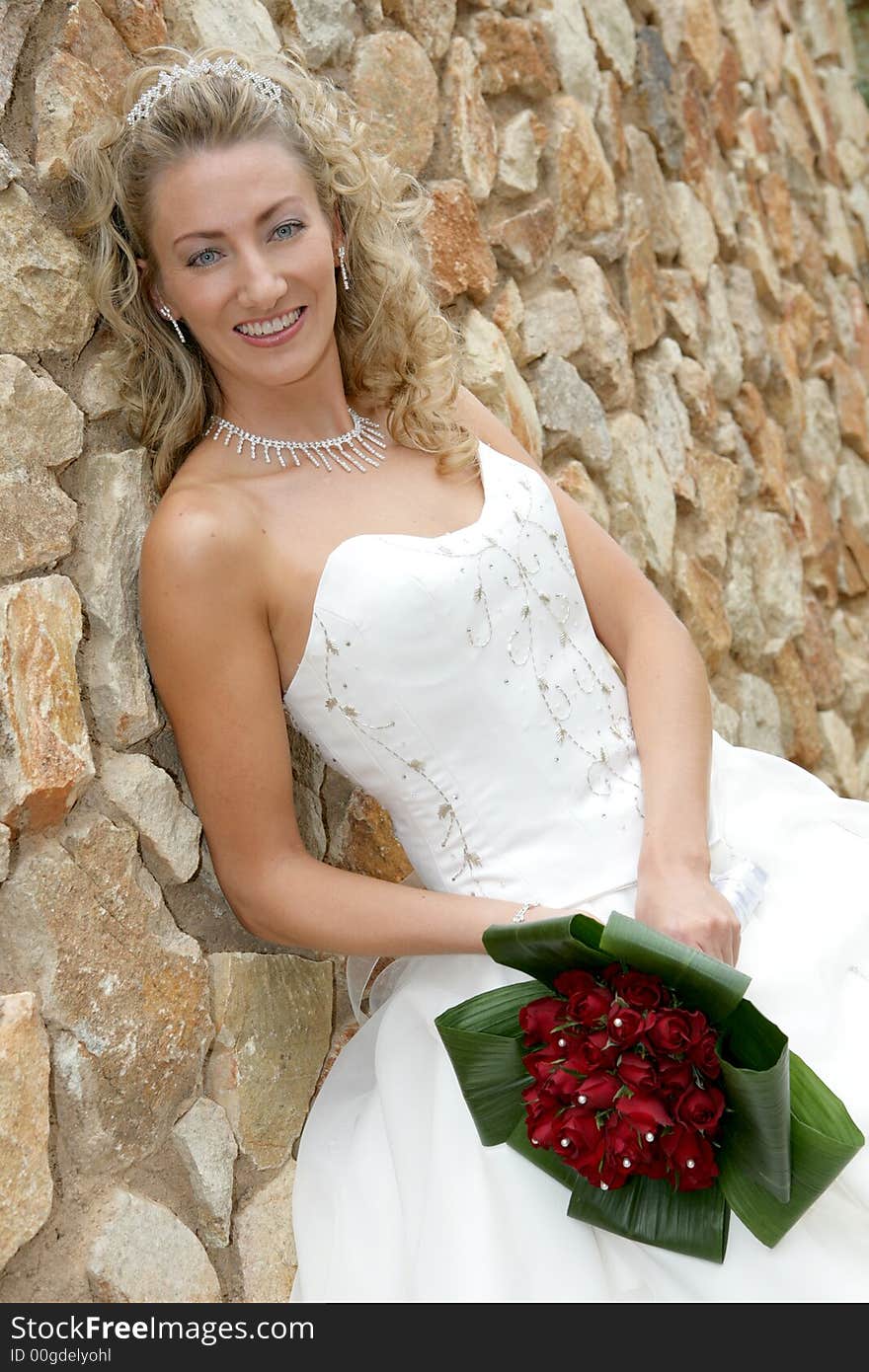 A bride standing against a stone wall