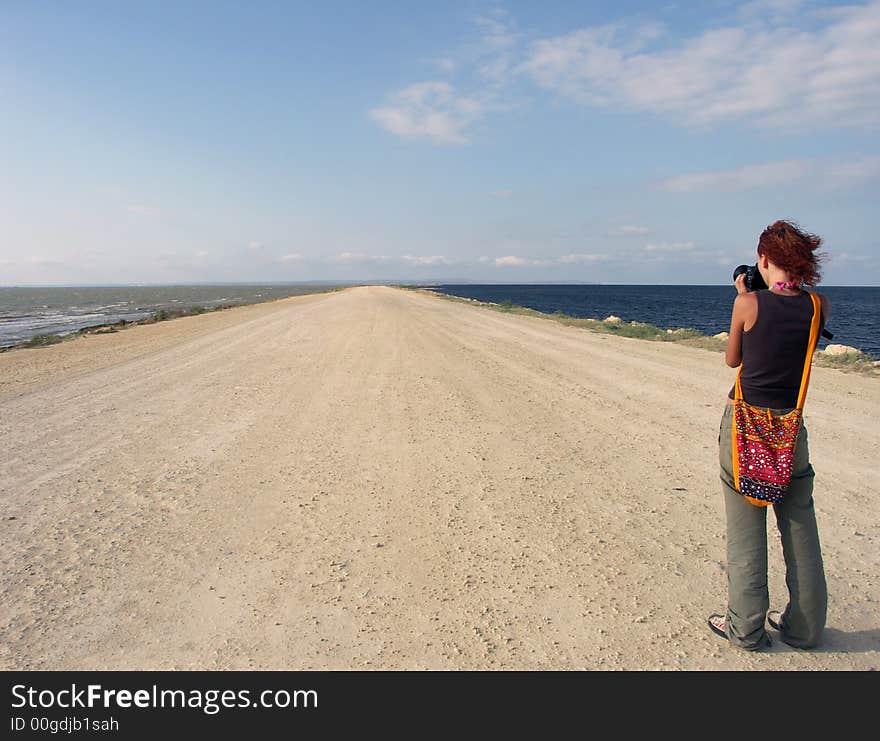 The girl on rest costs on road and looks at open spaces of the sea. The girl on rest costs on road and looks at open spaces of the sea