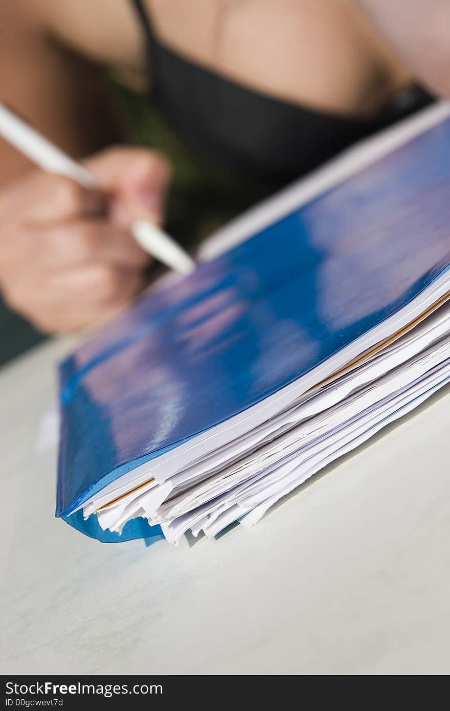 Stack of papers on the front and pencil in hand on background. Stack of papers on the front and pencil in hand on background