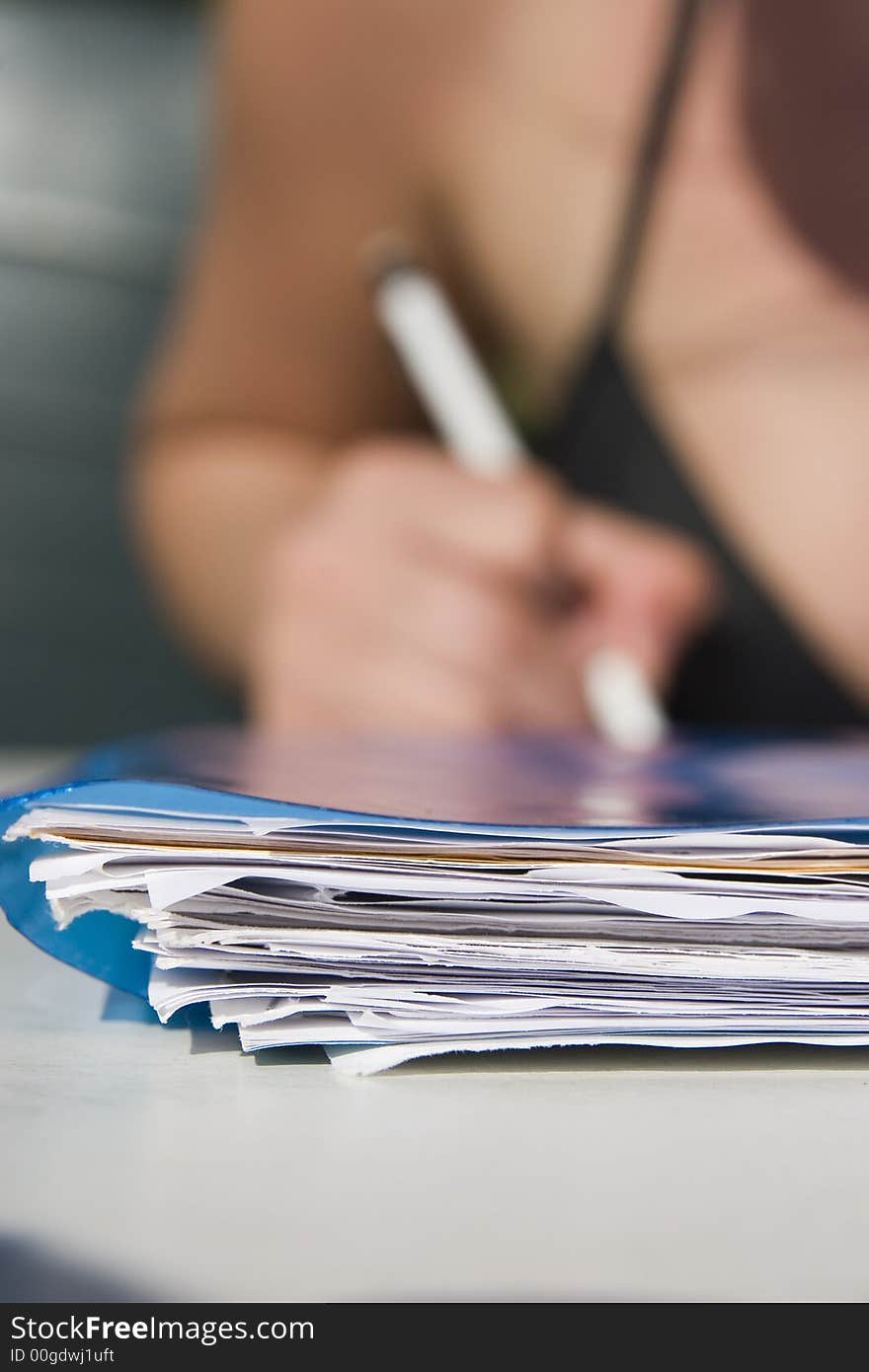 Stack of papers in front and pencel in hand in background. Stack of papers in front and pencel in hand in background