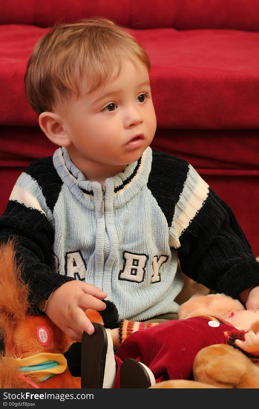 Little blond baby boy playing with toys at home