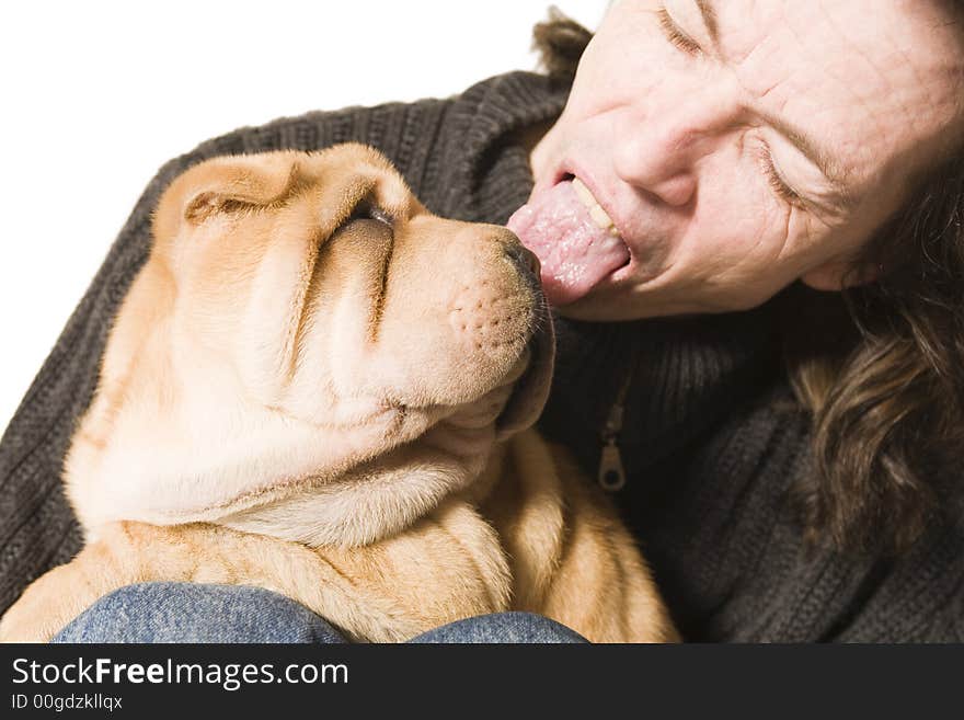 A funny young man licking a sharpei puppy over the head. A funny young man licking a sharpei puppy over the head