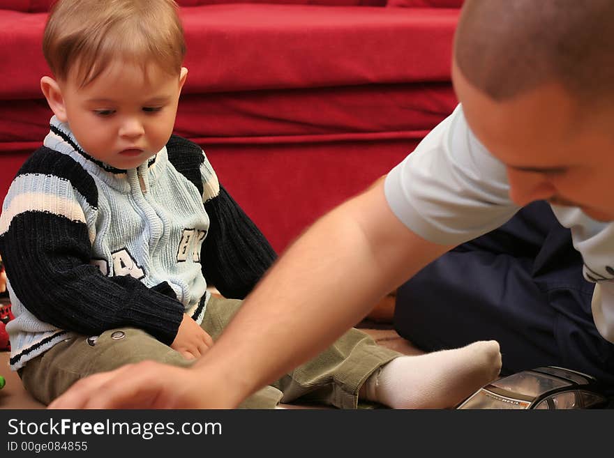 Little blond baby boy playing with toys at home with his father