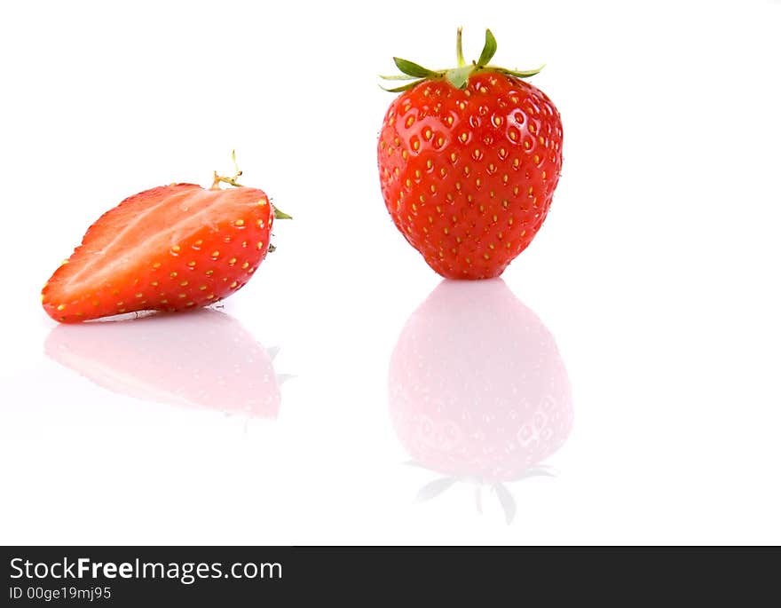 Full strawberry and half isolated over white with reflection. Full strawberry and half isolated over white with reflection