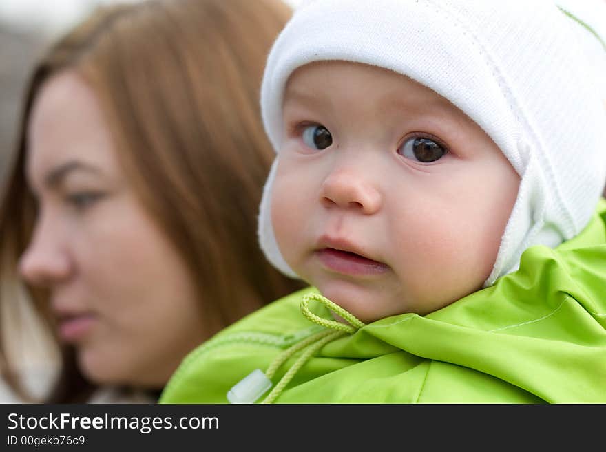 Little girl looking to the camera, mother's face is out of focus. Little girl looking to the camera, mother's face is out of focus