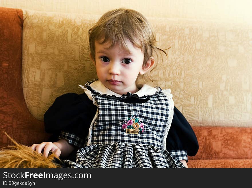 Little cute girl sitting on the sofa. Special yellow toned photo f/x