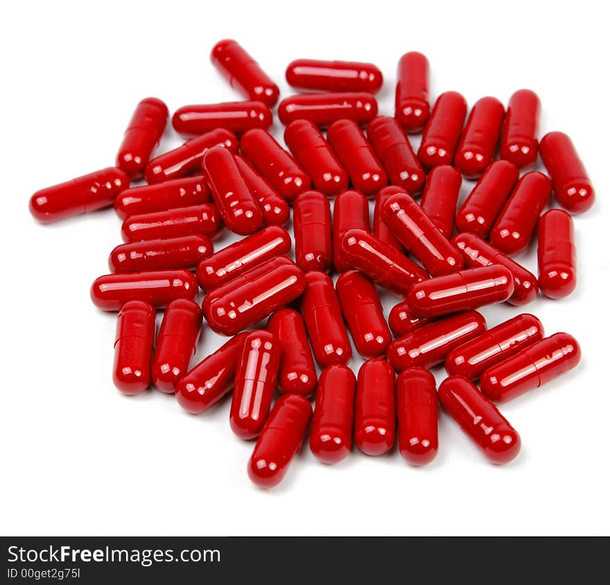 Red capsules upper view over white background.