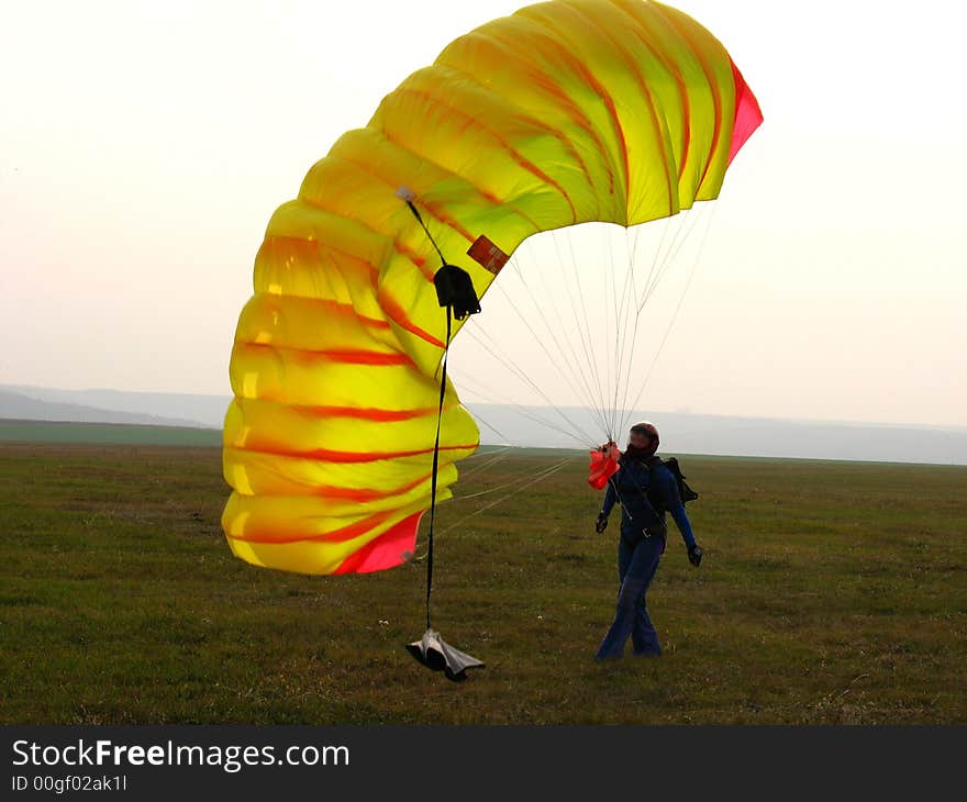 The parachuter lands on the ground, the parachute beautifully reveals. The parachuter lands on the ground, the parachute beautifully reveals