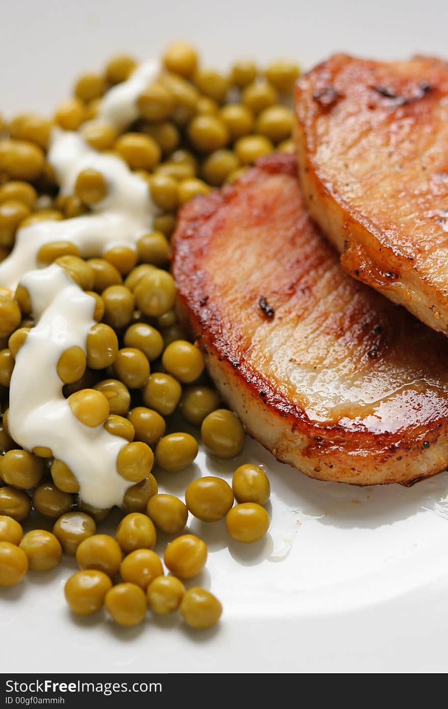 Pork and green peas within white plate