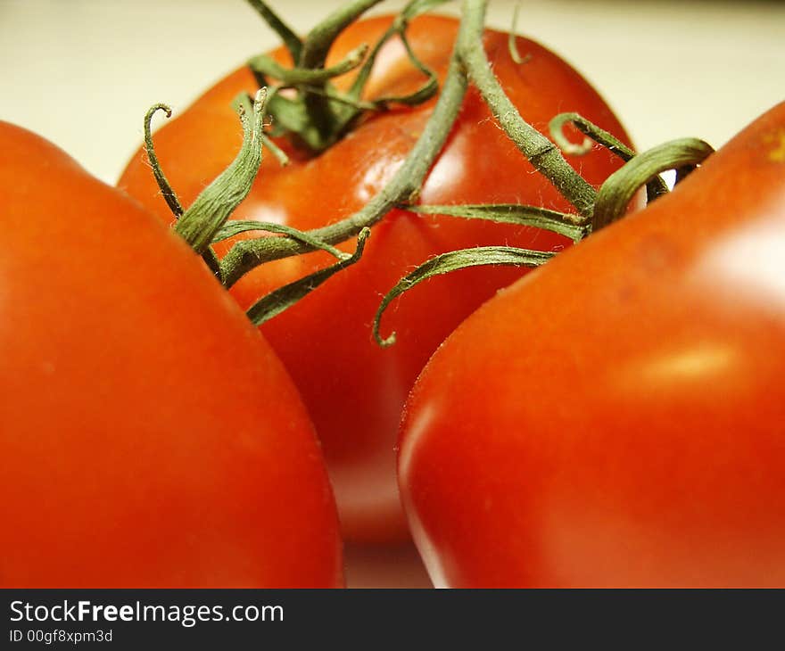 Bright red tomatoes still attached to the vine. Bright red tomatoes still attached to the vine.