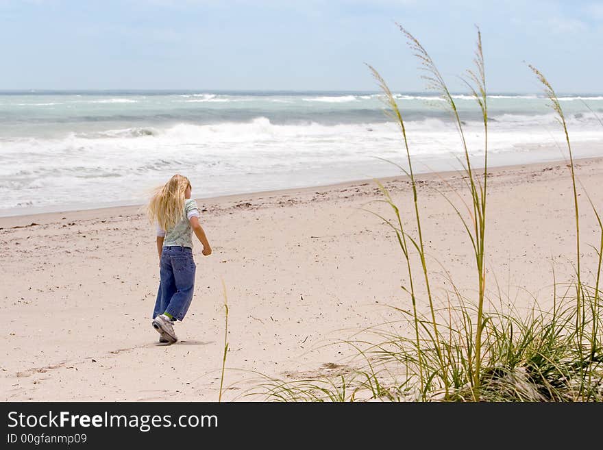 Young girl walking on the beach with Sea Oats in foreground. Young girl walking on the beach with Sea Oats in foreground