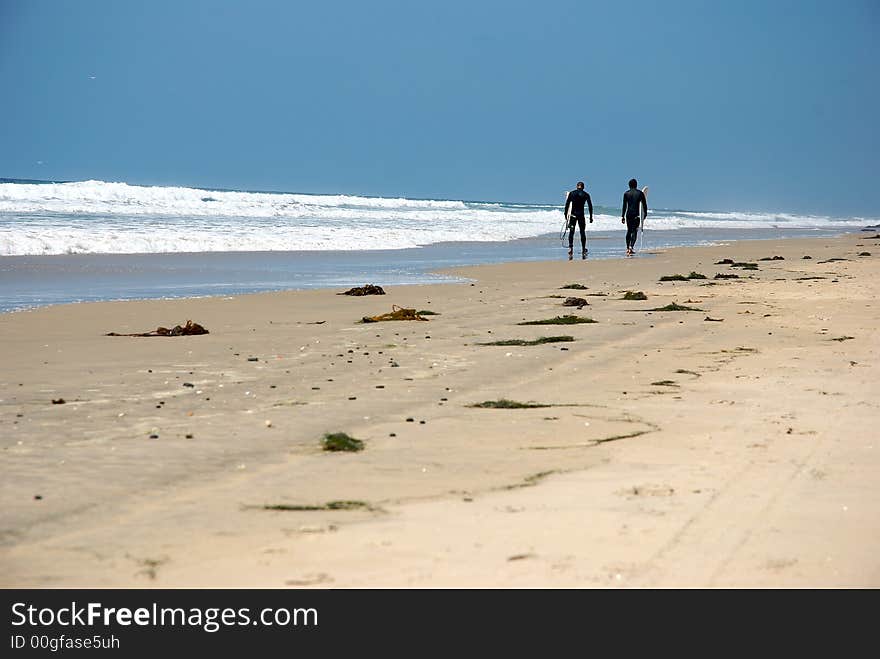 Two surfer walking by the beach