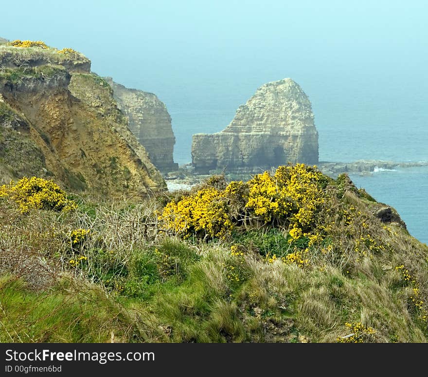 Pointe-Du-Hoc, Normandy, France with a hazy blue sky in the background