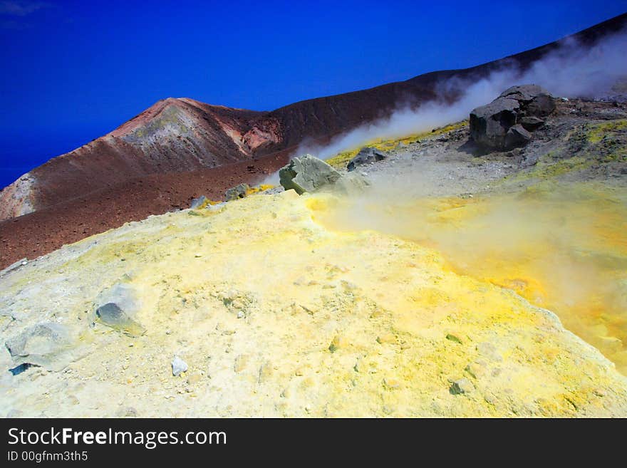 Rocks, smoke and sulphur on the volcano by a sunny day.