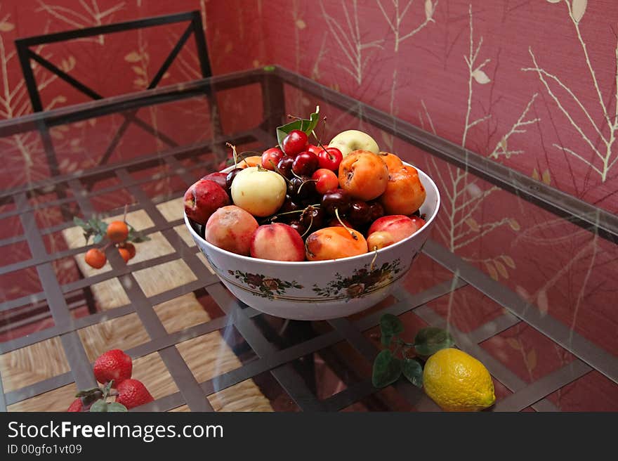 Plateful decorated by colors of fruit on red kitchen