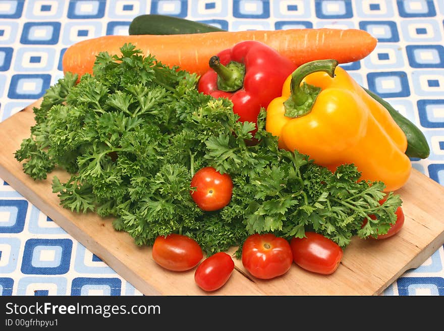 Parsley, cherry tomatoes, capsicums, carrot and cucumber on wooden board. Parsley, cherry tomatoes, capsicums, carrot and cucumber on wooden board