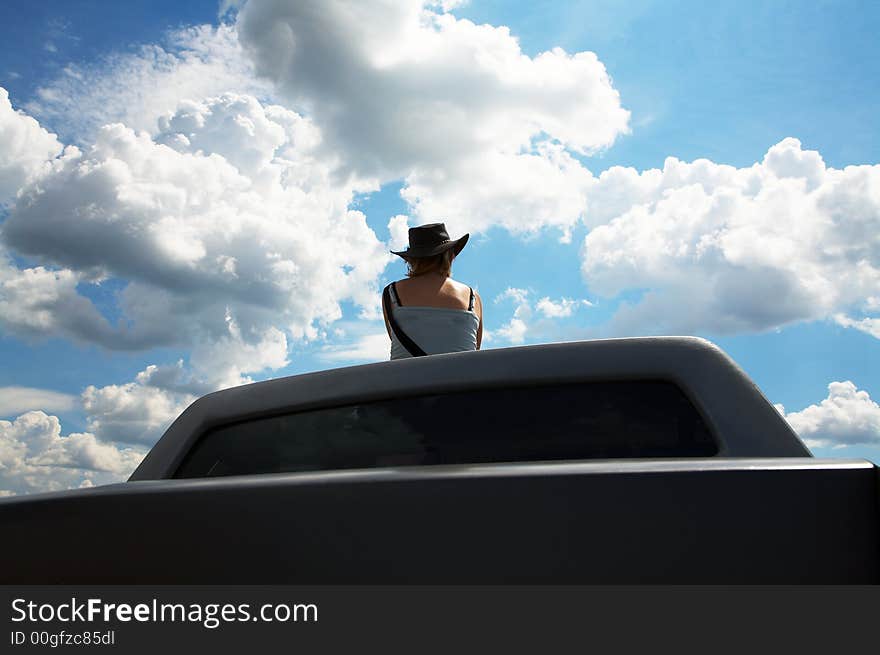 The girl in a cowboy's hat on a roof of the car