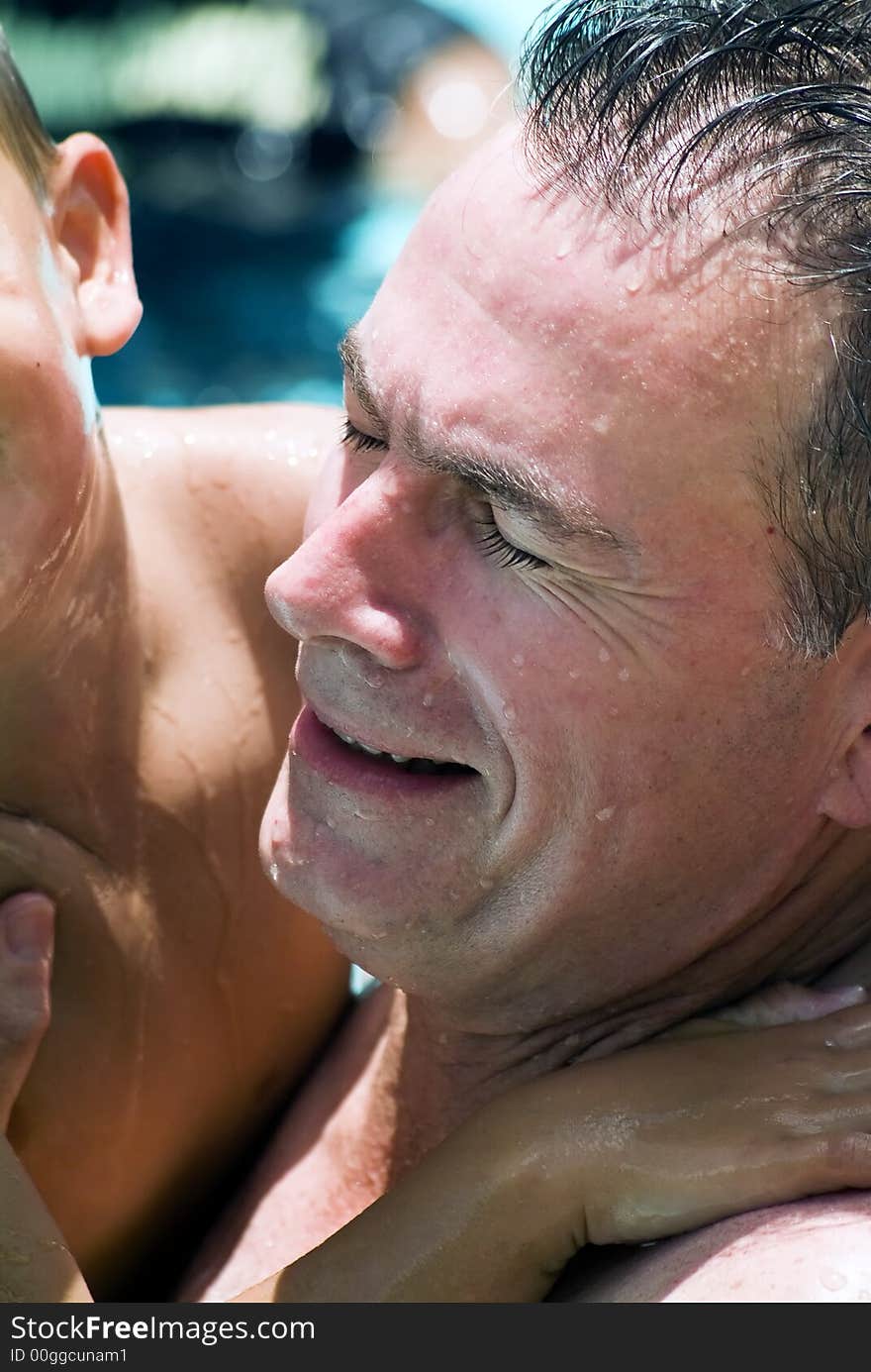 A wet man and a little boy engaged in rowdy play in a pool. A wet man and a little boy engaged in rowdy play in a pool.