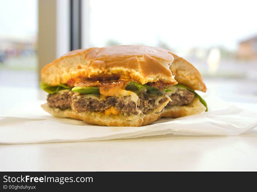 A half eaten hamburger sitting on a table. A half eaten hamburger sitting on a table