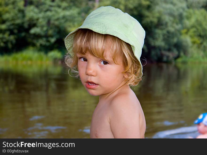 Little kid stands near river