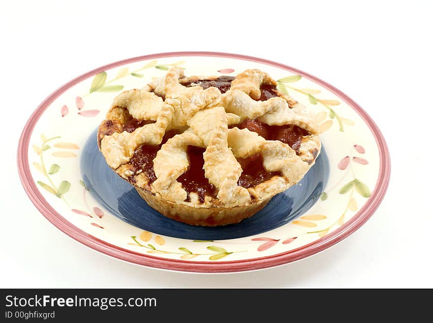 An individual cherry peach pie with lattice crust on an interesting plate.