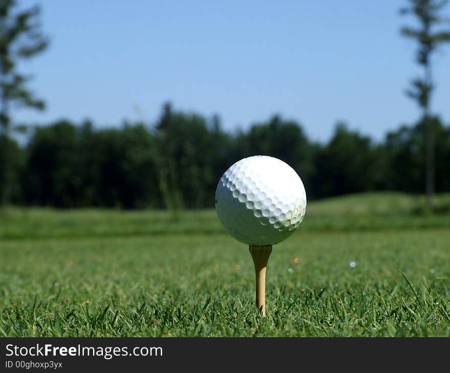 A golf ball on a tee on a course. A golf ball on a tee on a course