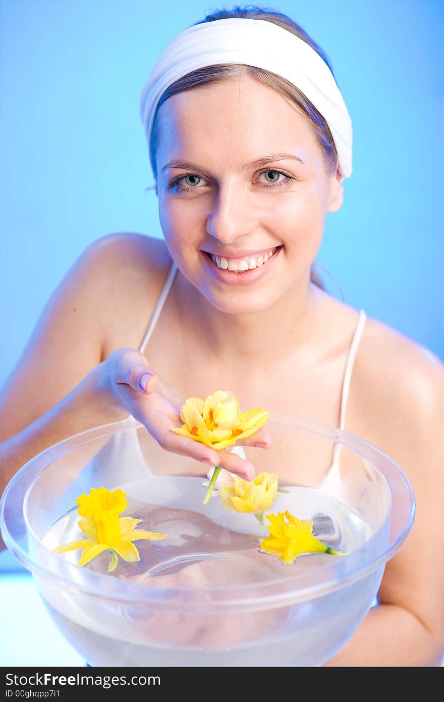 Beautiful young woman is holding one of the flowers that are in a bowl of water. Beautiful young woman is holding one of the flowers that are in a bowl of water