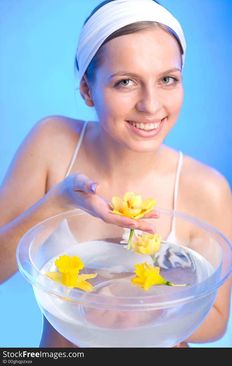 Beautiful young woman is holding one of the flowers that are in a bowl of water. Beautiful young woman is holding one of the flowers that are in a bowl of water