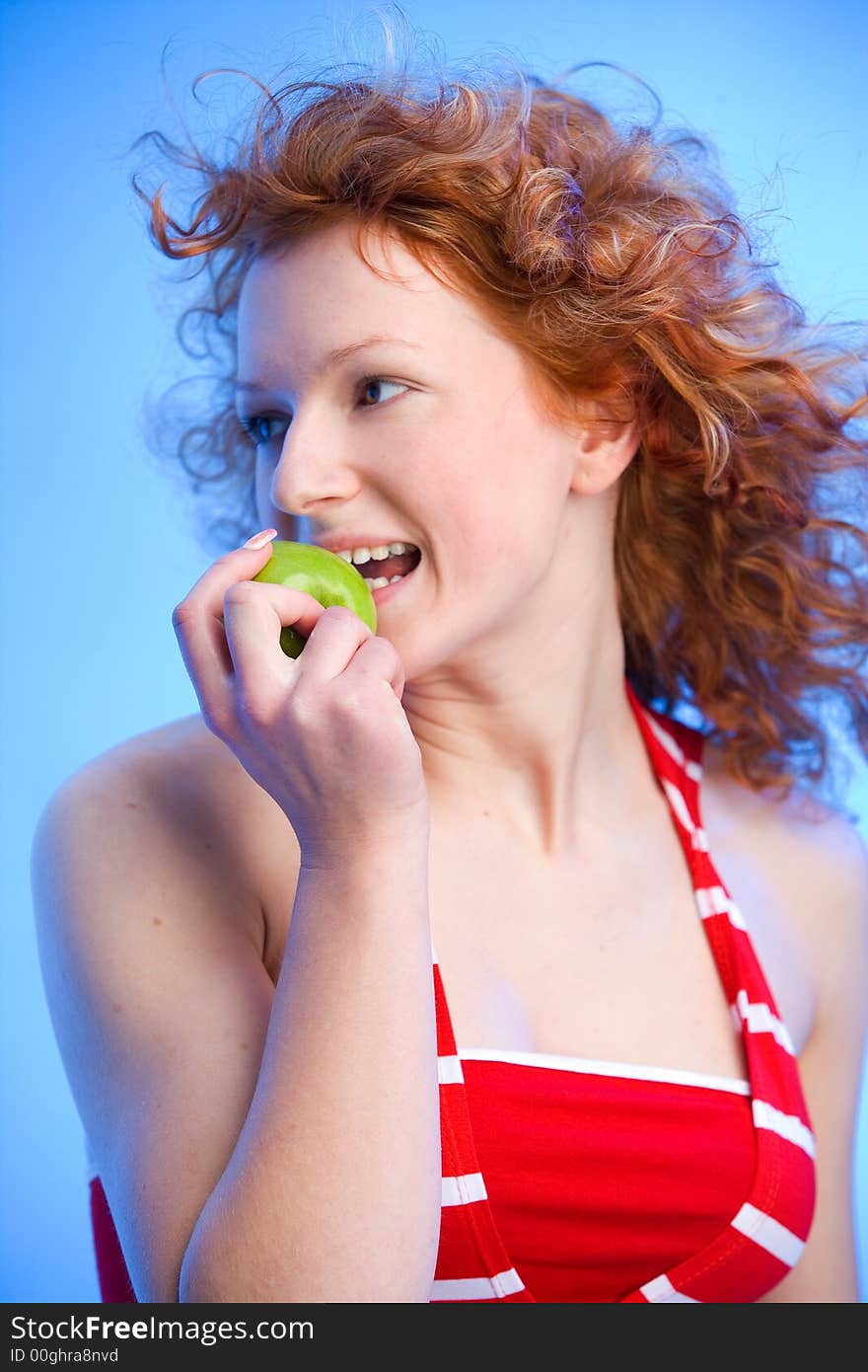 Beautiful redhaired girl is biting off a green apple. Beautiful redhaired girl is biting off a green apple