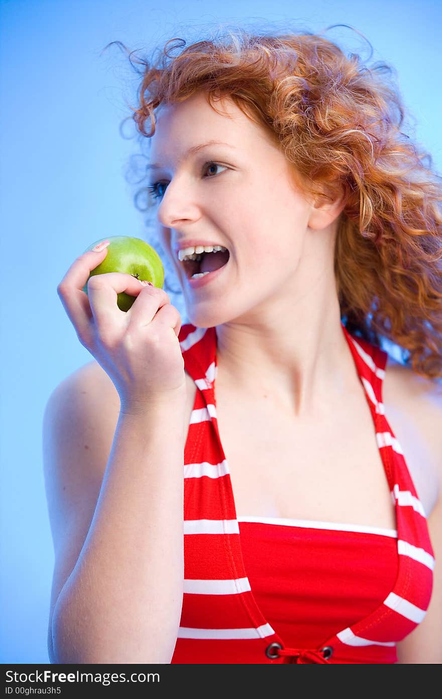 Beautiful redhaired girl is biting off a green apple. Beautiful redhaired girl is biting off a green apple