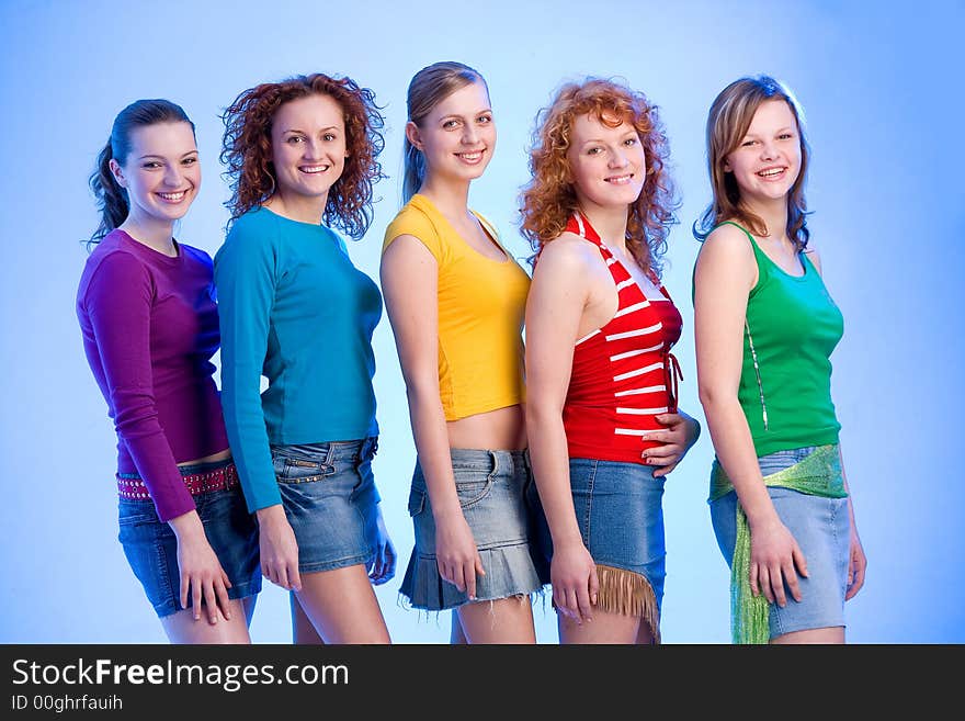 Five happy young girlfriends wearng colourful shirts and miniskirts are standing in a row. Five happy young girlfriends wearng colourful shirts and miniskirts are standing in a row