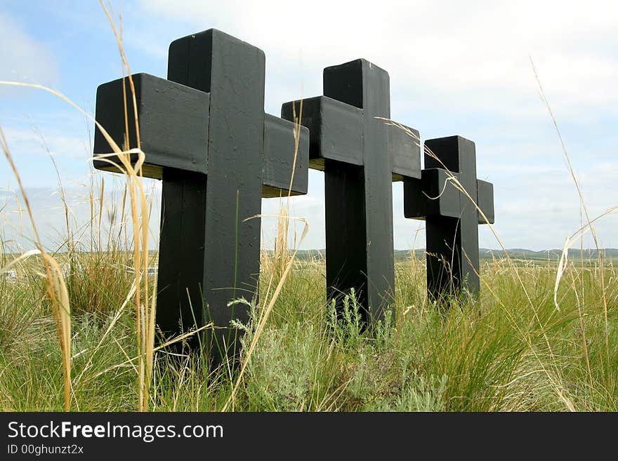 Three black crosses in a grass on a background of the sky