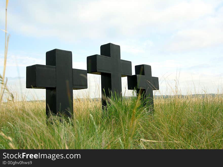 Three black crosses in a grass on a background of the sky